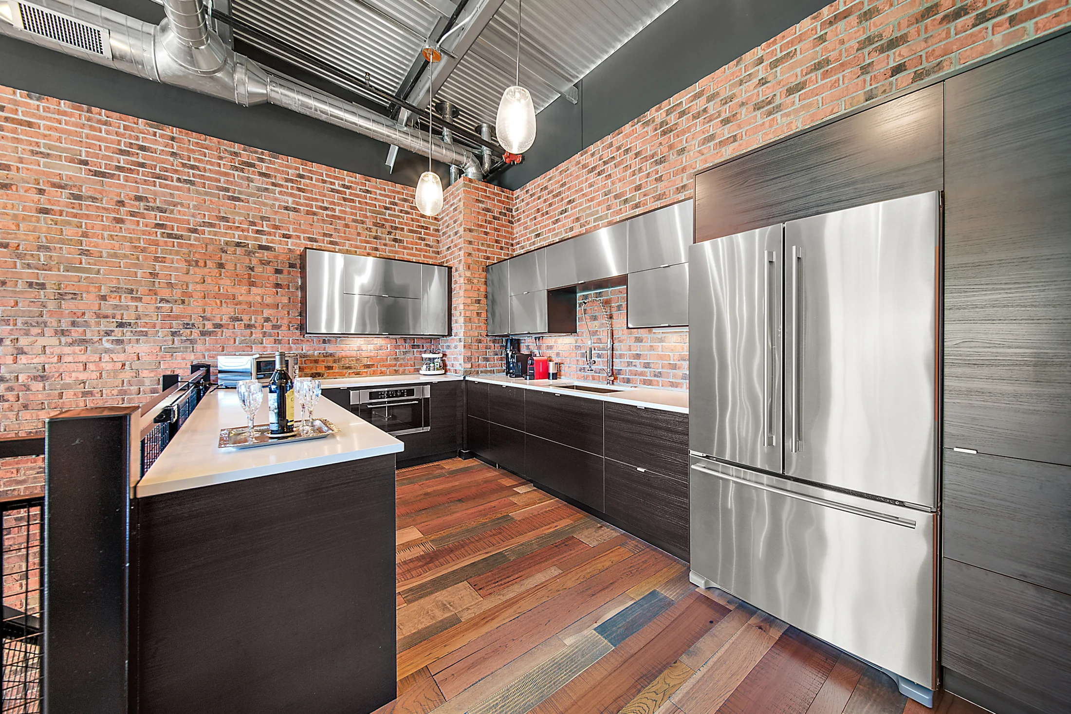 The upper-level kitchen, with dark cabinetry, stainless-steel finishes and exposed brick.