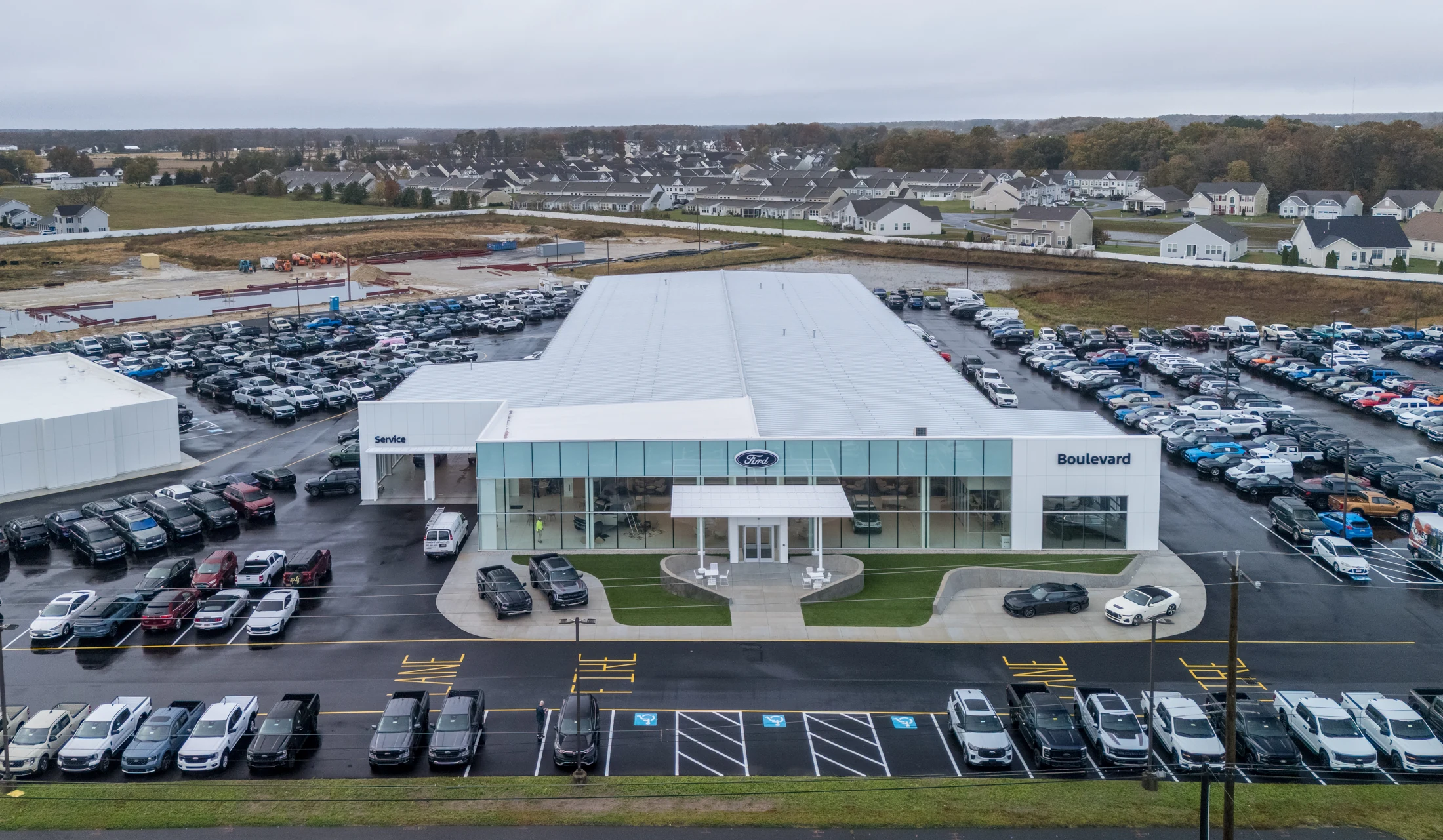 Boulevard Ford seen from above, with the entry trellis, Ford badge, glazed showroom and a complete dealer site full of vehicles