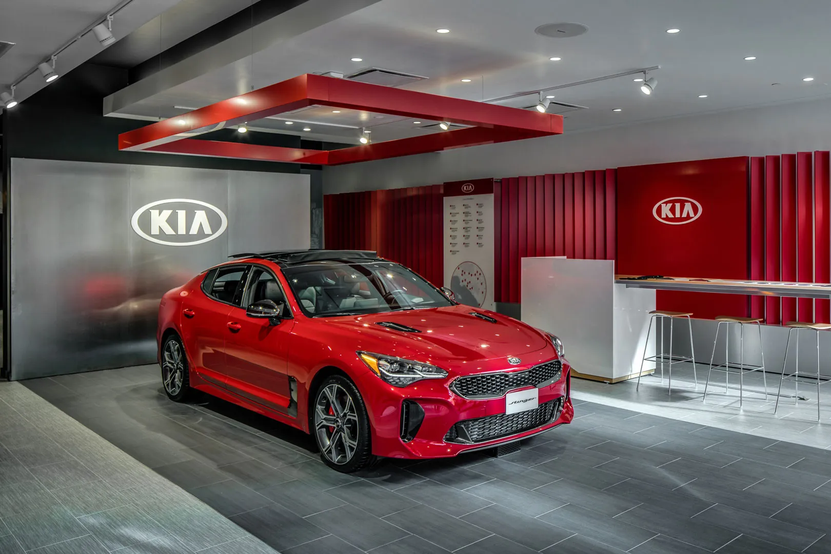 Kia Stinger Salon: a red vehicle displayed within a branded interior with sculptural red fins